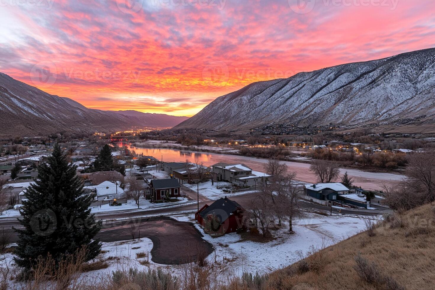 A colorful sunset over a town with snow and mountains photo