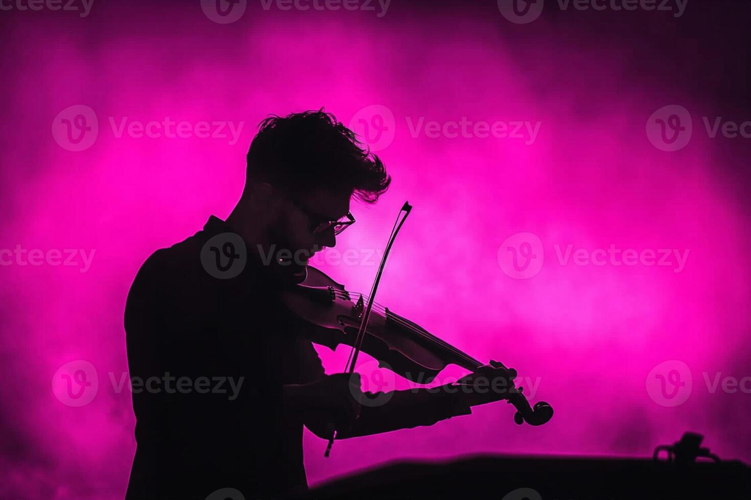 A man playing the violin in front of a pink light photo