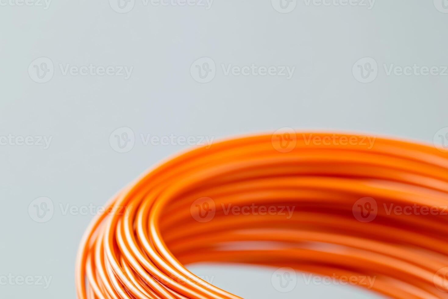 Orange wire coil twisted neatly for crafting projects or electrical use in a workspace photo