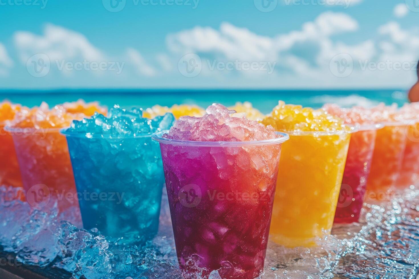 Colorful cups of shaved ice with syrup lined up by the beach with ocean views and bright blue skies photo