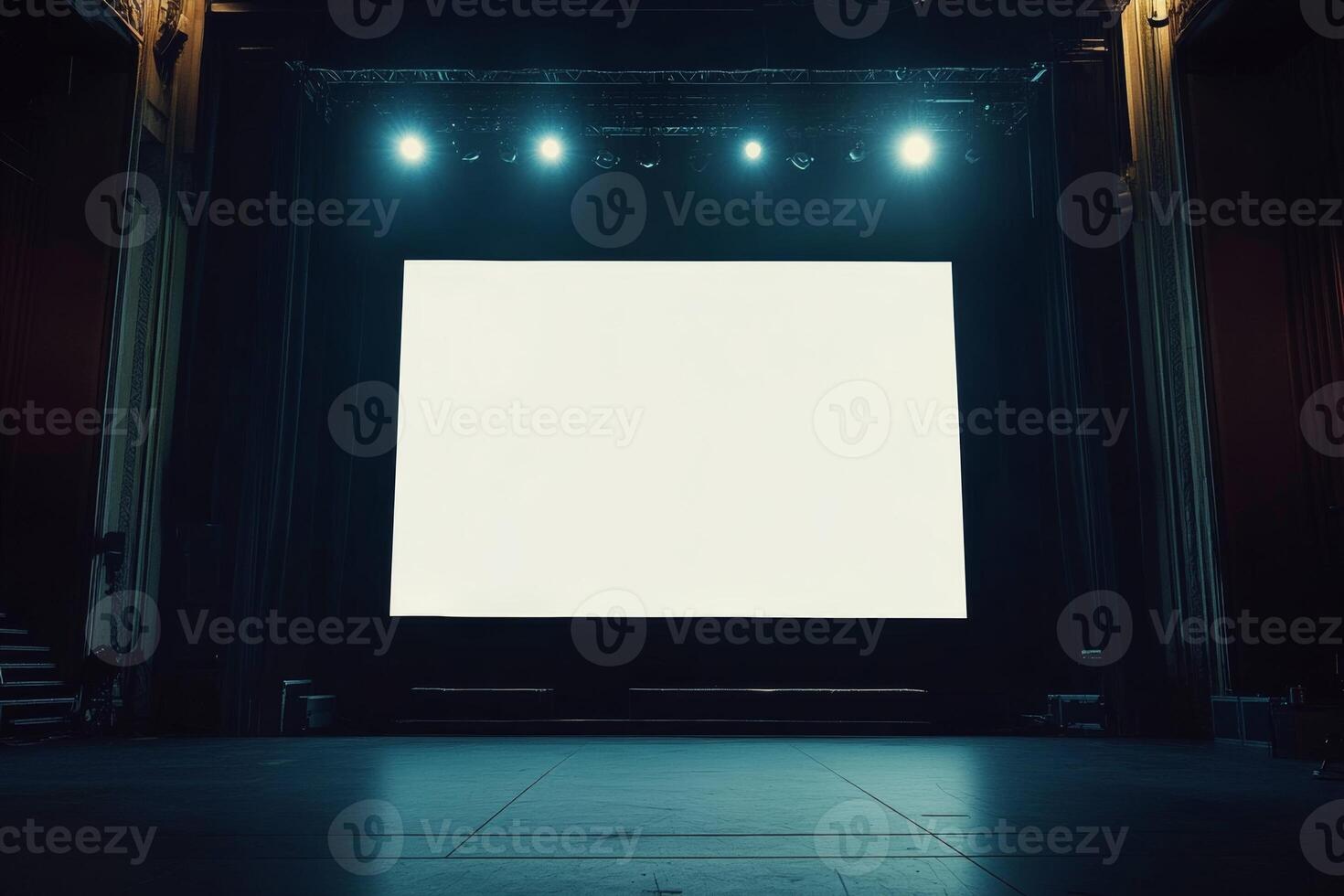 A large blank screen on stage in a concert hall illuminated by bright lights against a dark background photo