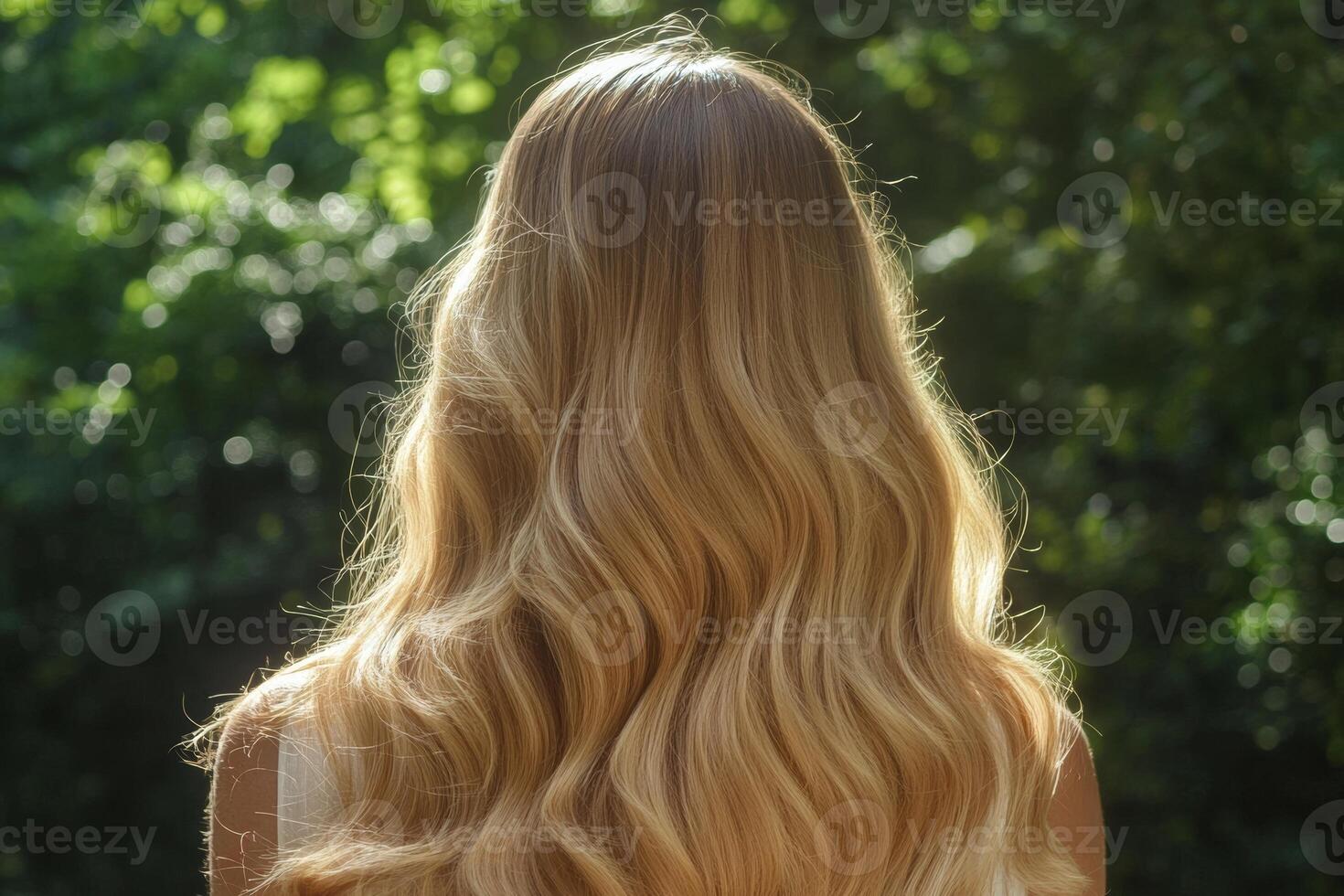 A woman admiring her long, shiny blonde hair illuminated by the golden hour sunlight in a lush, natural setting photo