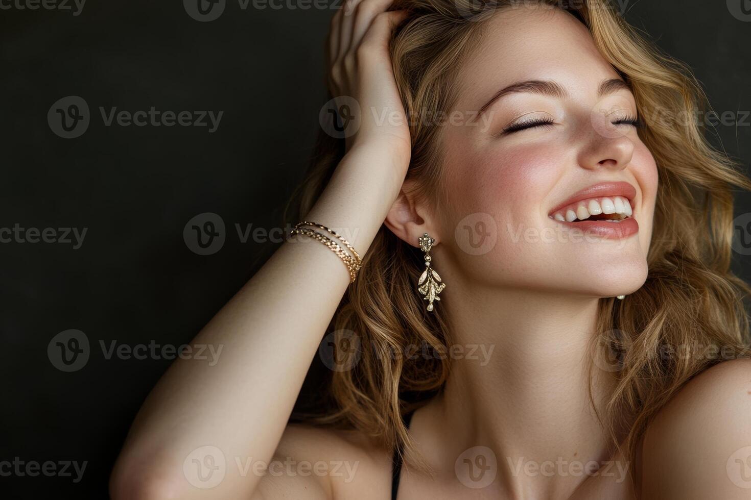 Joyful woman showcases elegance and charm in a studio setting with beautiful earrings and a bracelet photo