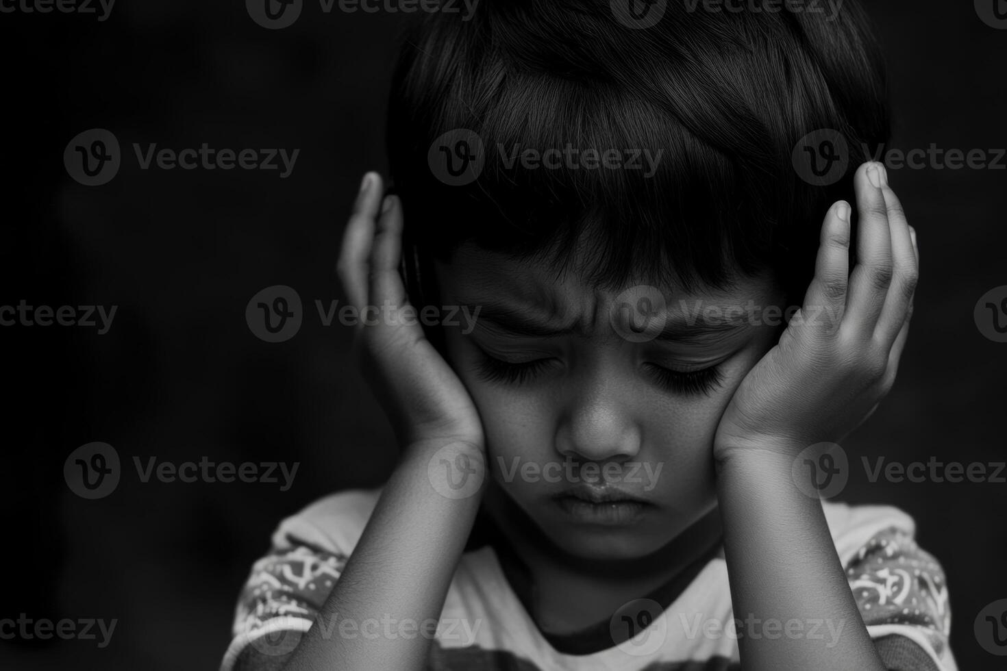Sad child covering his ears in distress, expressing emotions in a dark environment photo