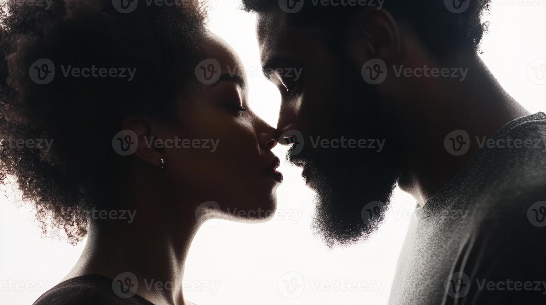 A loving black couple sharing a kiss and gazing into each other's eyes against a white backdrop, embodying true romance and connection photo