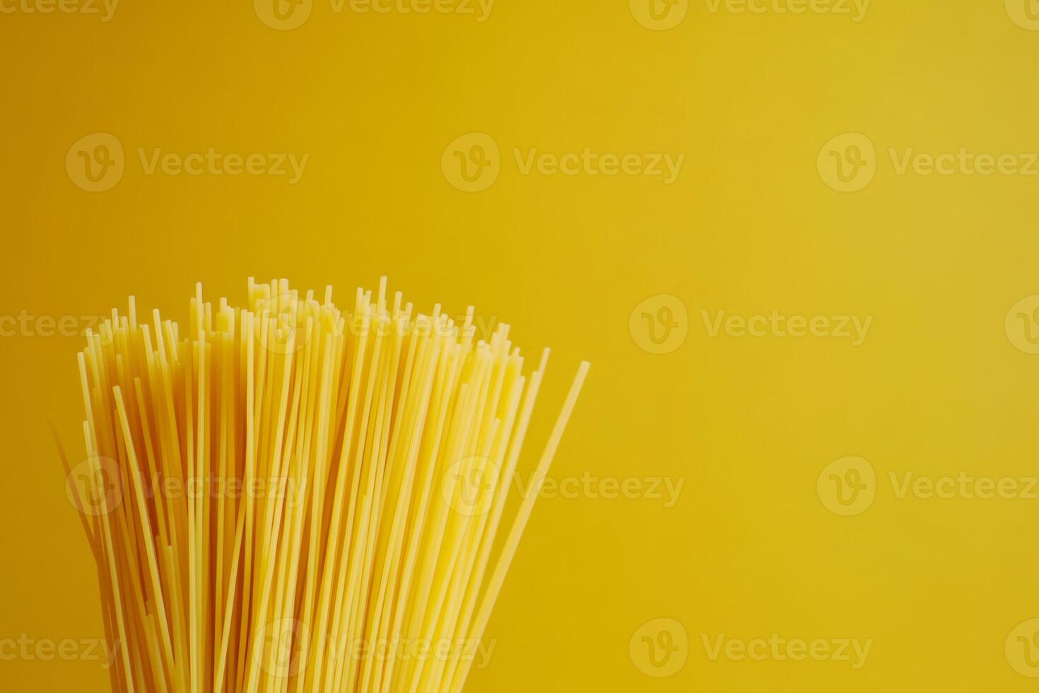 Fresh spaghetti prepared for a delightful meal against a bright yellow background with ample copy space for creative use photo