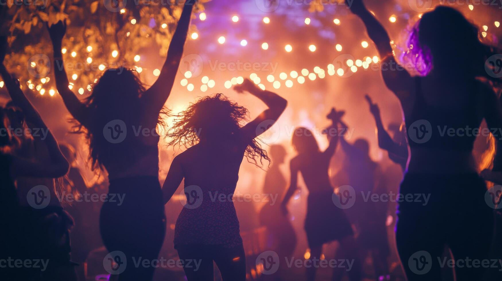 People dancing joyfully at an outdoor concert party with vibrant lights during a lively summer evening celebration photo