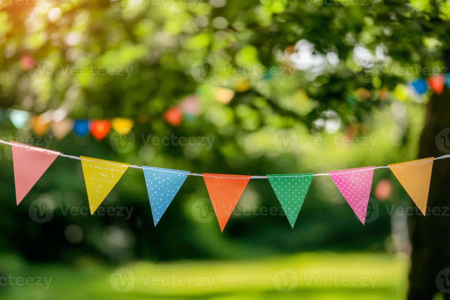 Festive outdoor event with colorful flags strung across a sunny park setting, creating a joyful celebration atmosphere photo