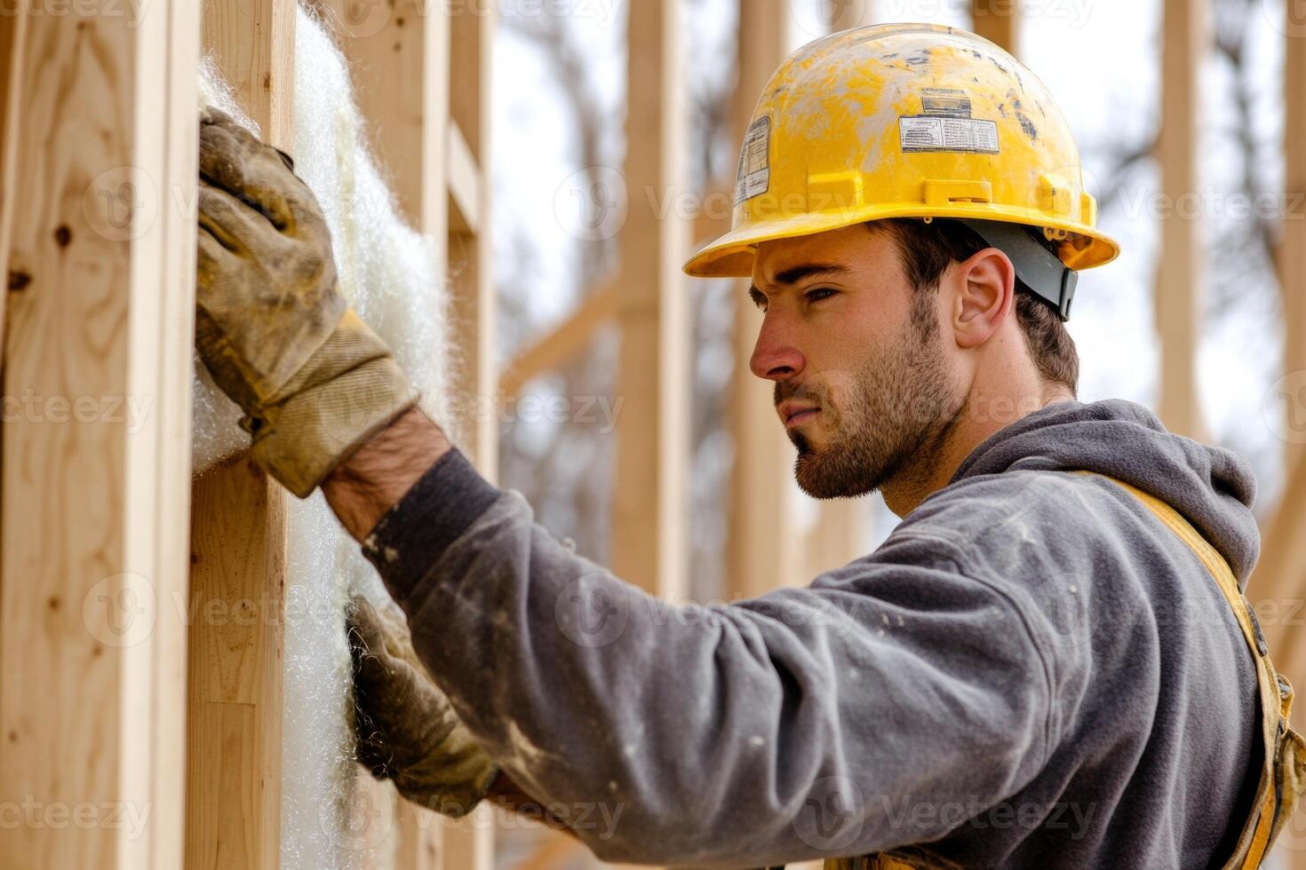 Construction worker carefully installs insulation in a wooden wall frame for energy efficiency in a new home photo