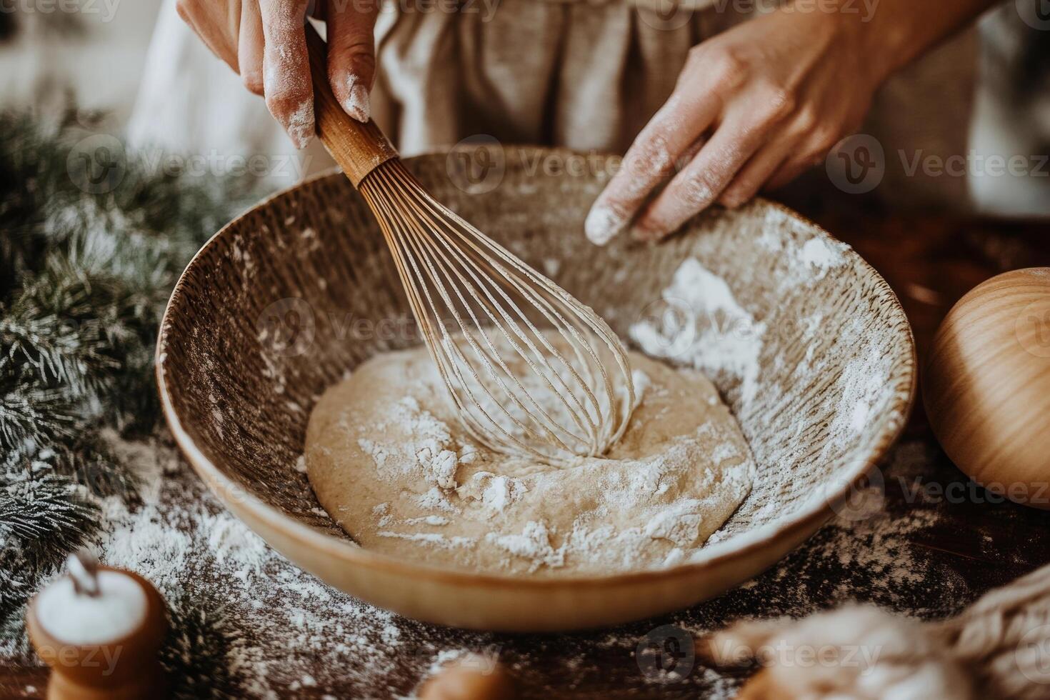 Close-up of hands whisking dough in a rustic bowl surrounded by winter decor, perfect for holiday baking inspiration photo