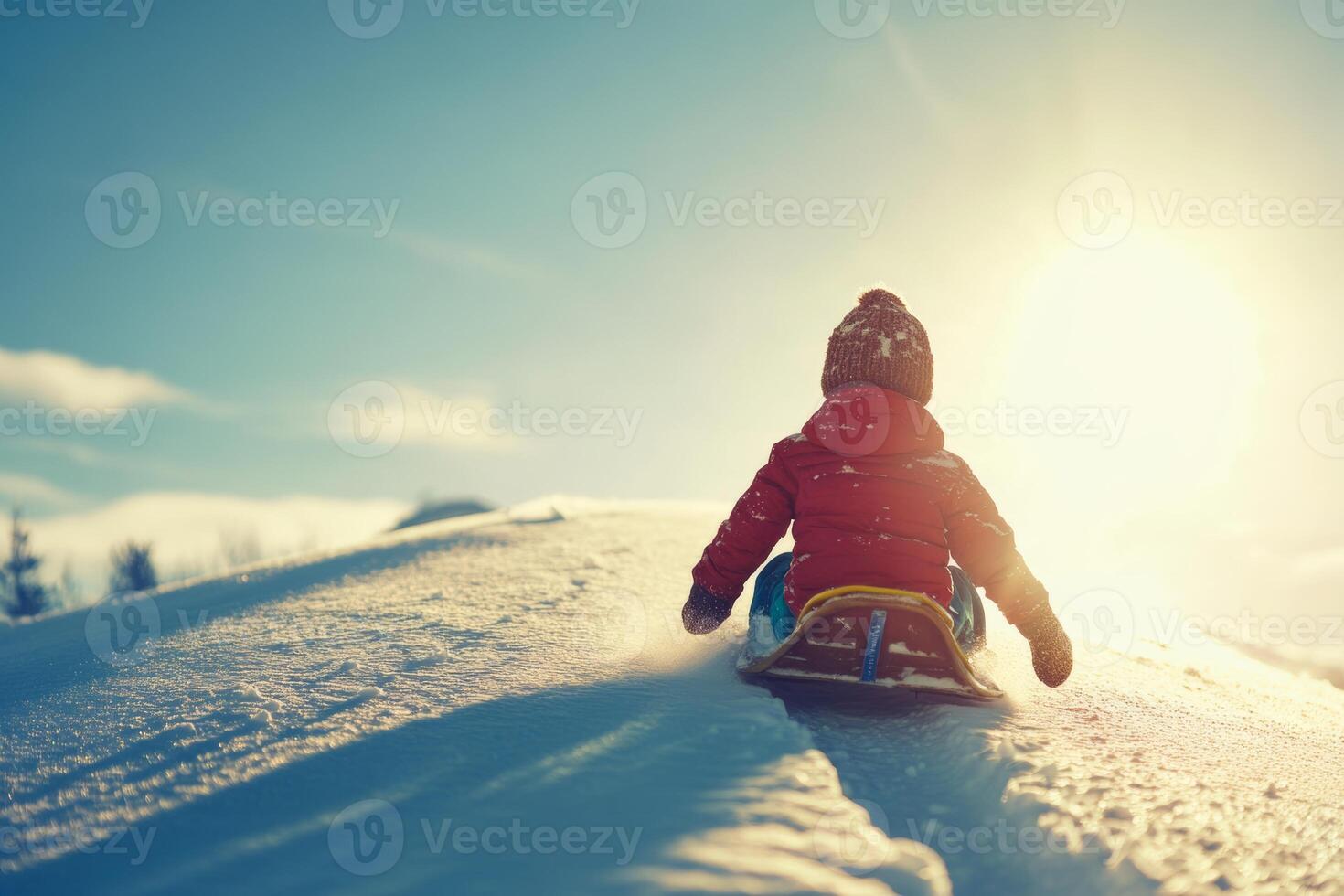 A joyful child sledding down a snowy hill on a bright winter day with warm sunlight illuminating the landscape photo