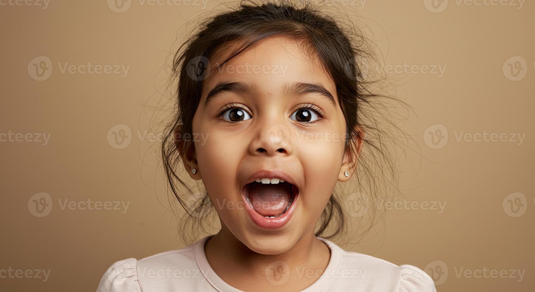 Adorable little girl expresses joy with a surprised expression indoors photo
