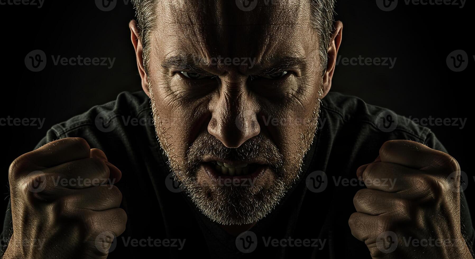 Angry middle-aged man shows rage with clenched fists and intense stare photo