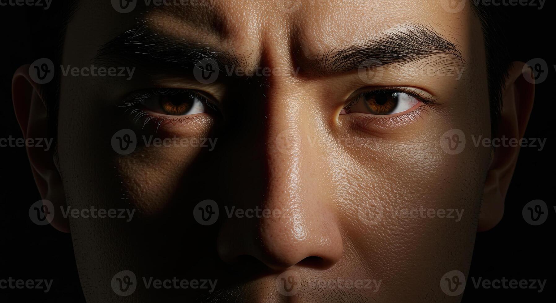 Close up of a serious Asian man's face in shadow displaying emotion photo