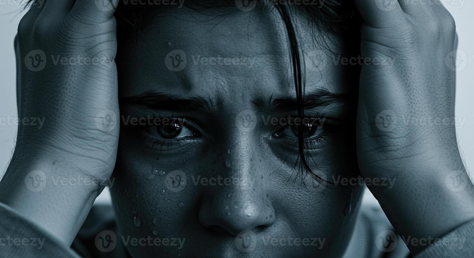 Close up of a young woman with tears and hands on her head in despair photo