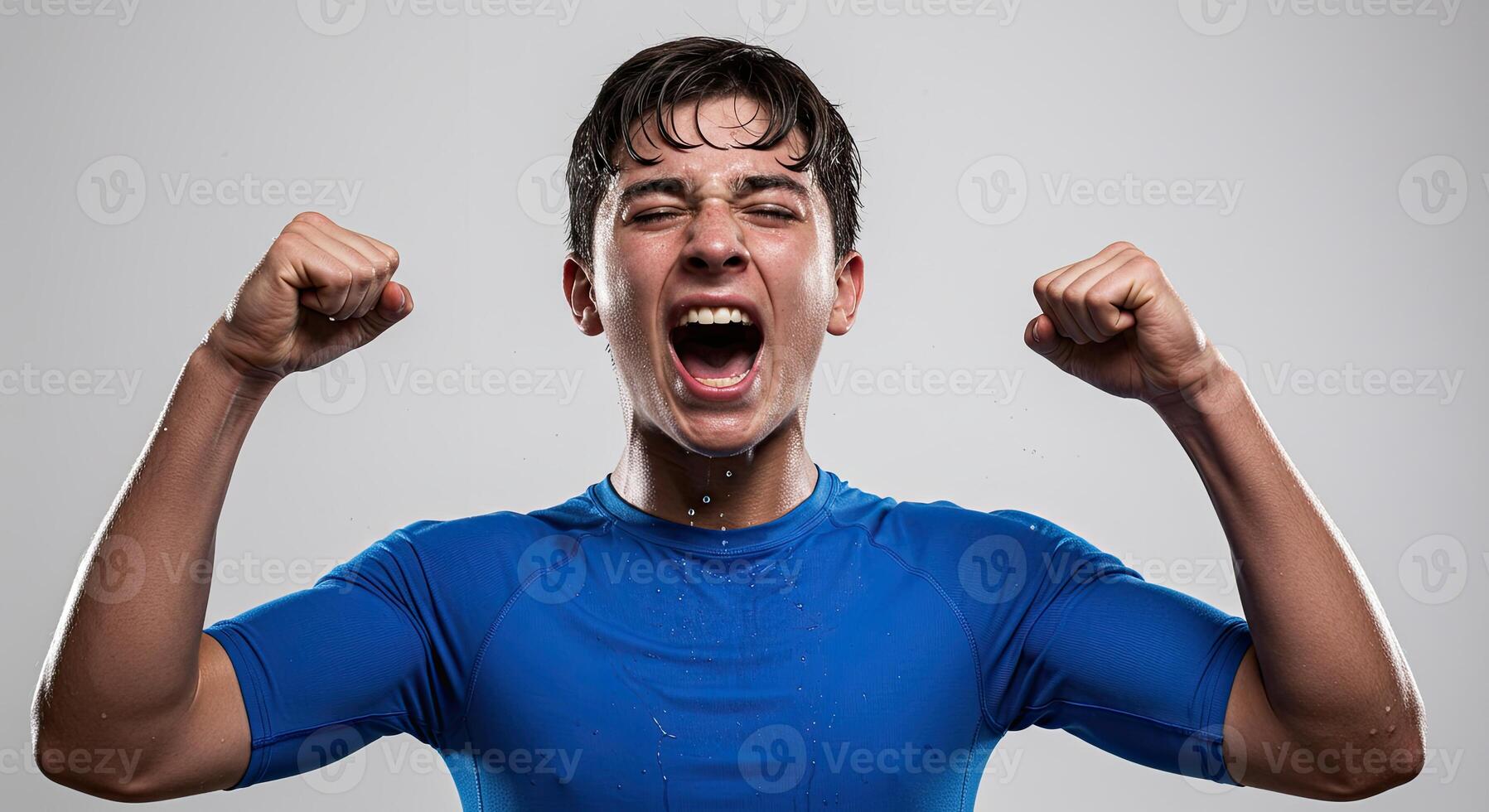 Ecstatic young man in blue shirt celebrates success with clenched fists photo