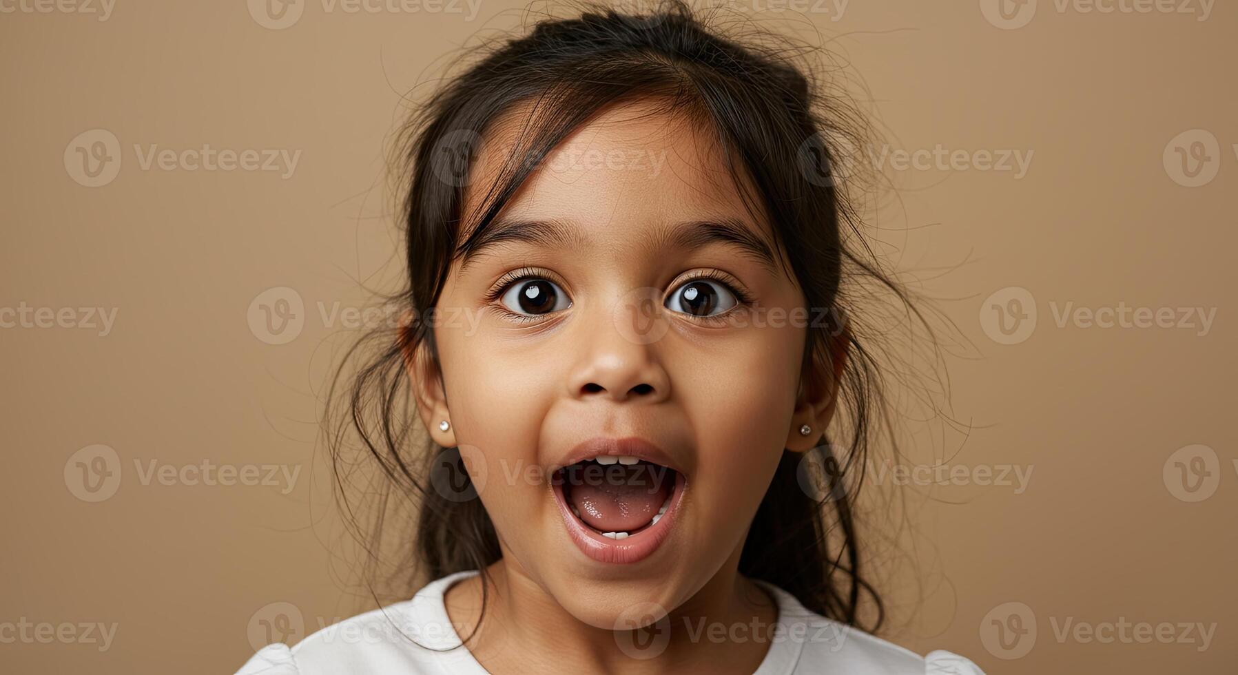 Excited little girl with surprised expression looks directly at camera photo