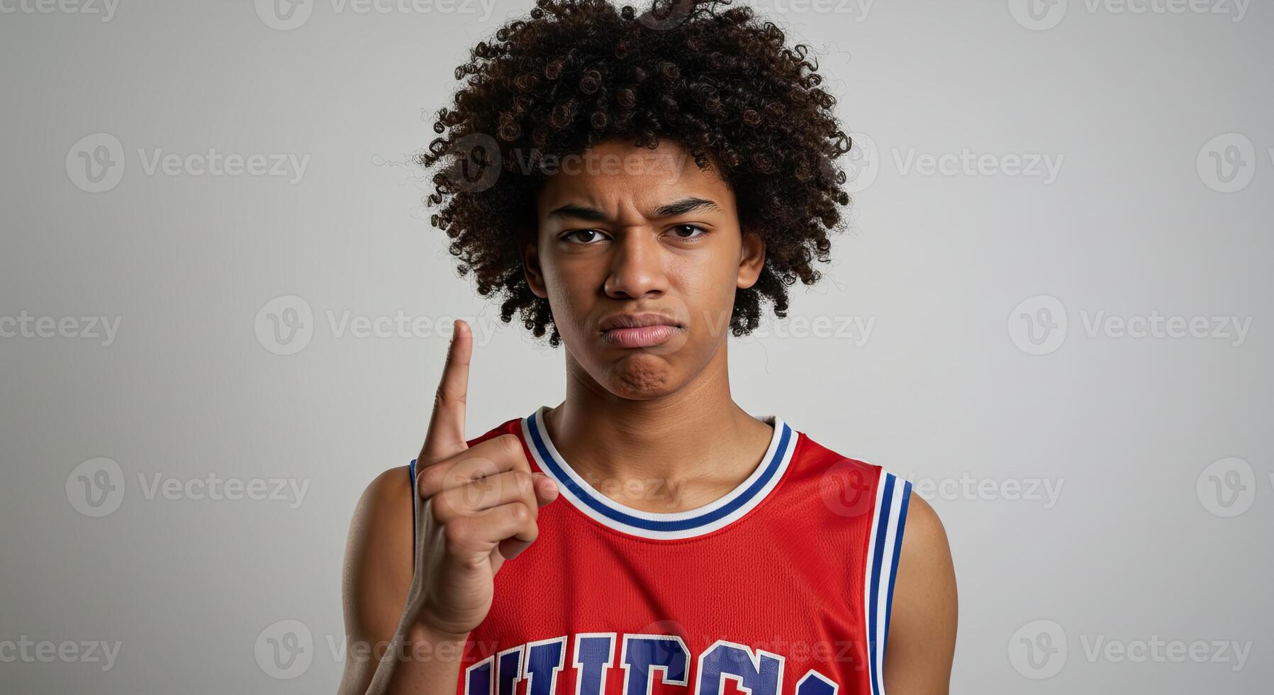 Serious young man in sports jersey raising finger with a warning gesture photo