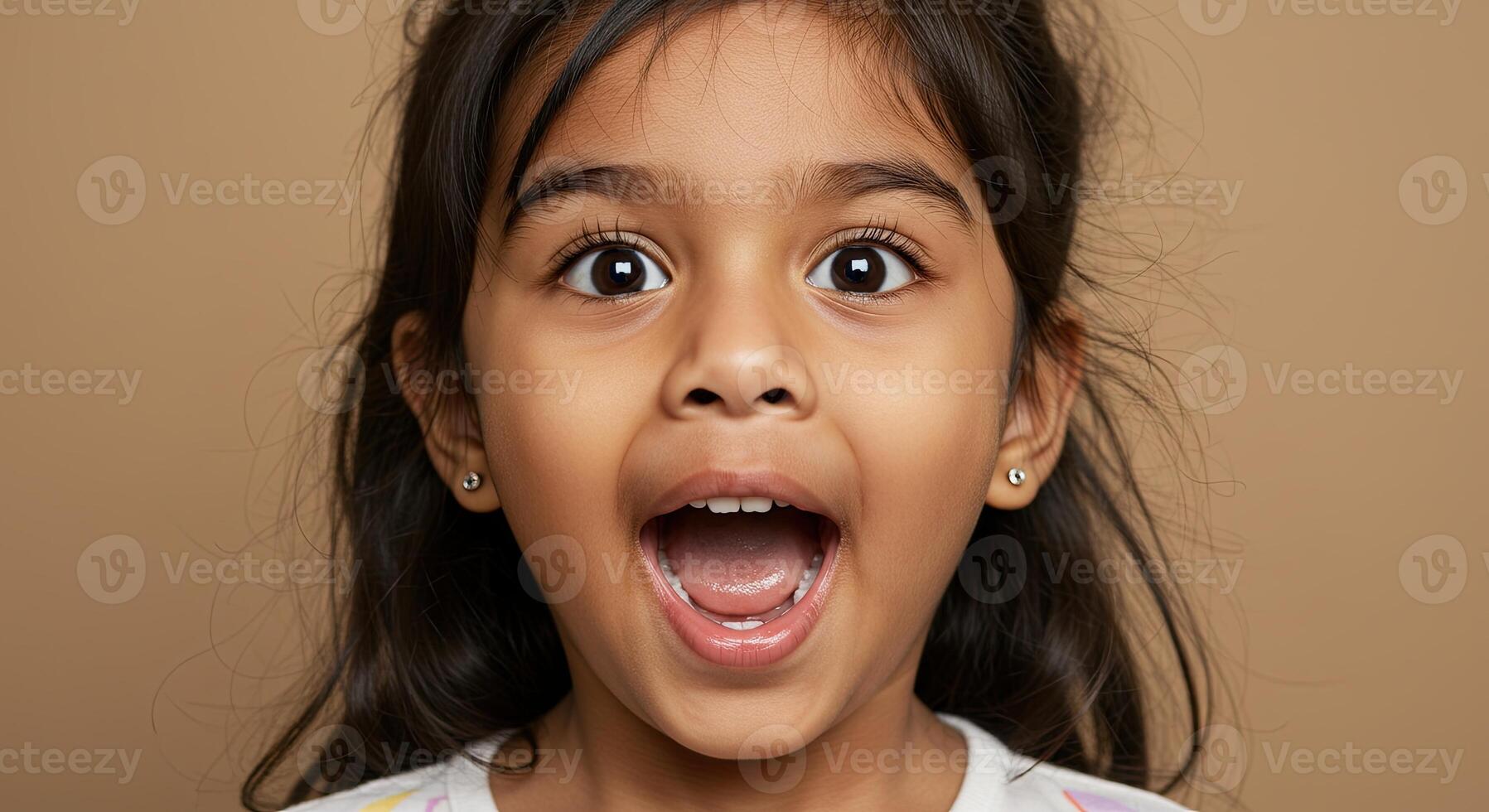 Surprised little girl with wide eyes and open mouth expresses excitement photo