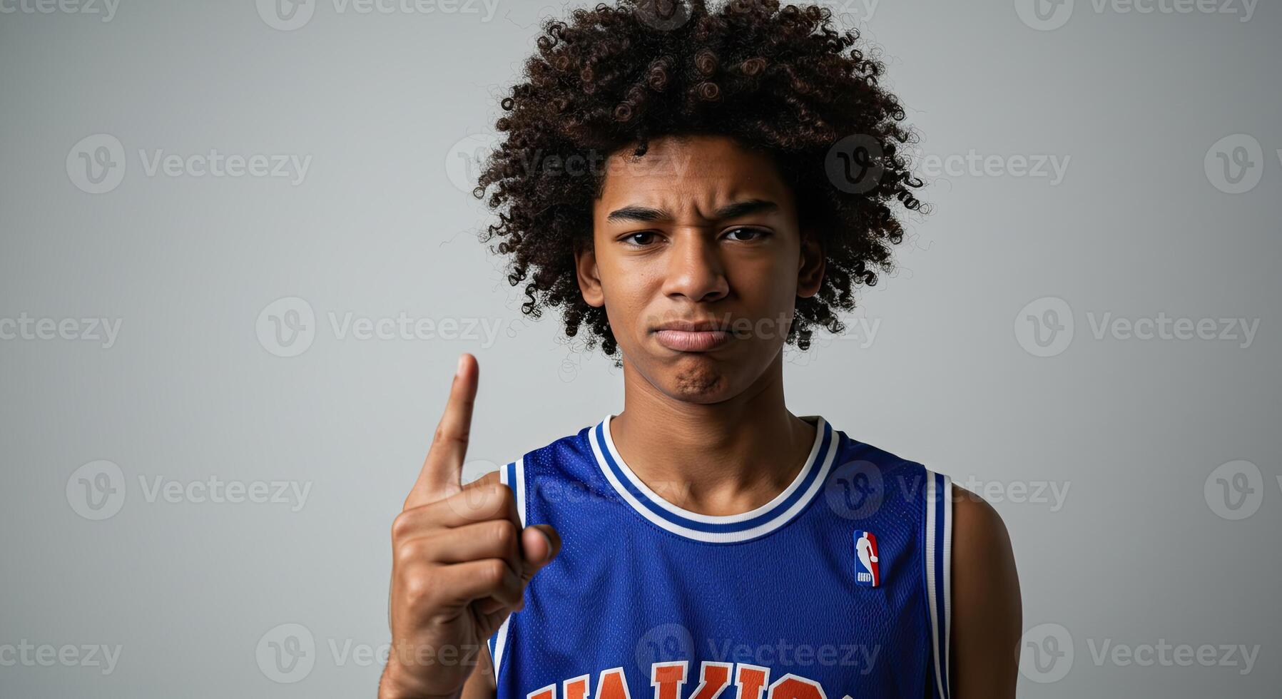 Teen boy in basketball jersey with finger up warns about rules violation photo