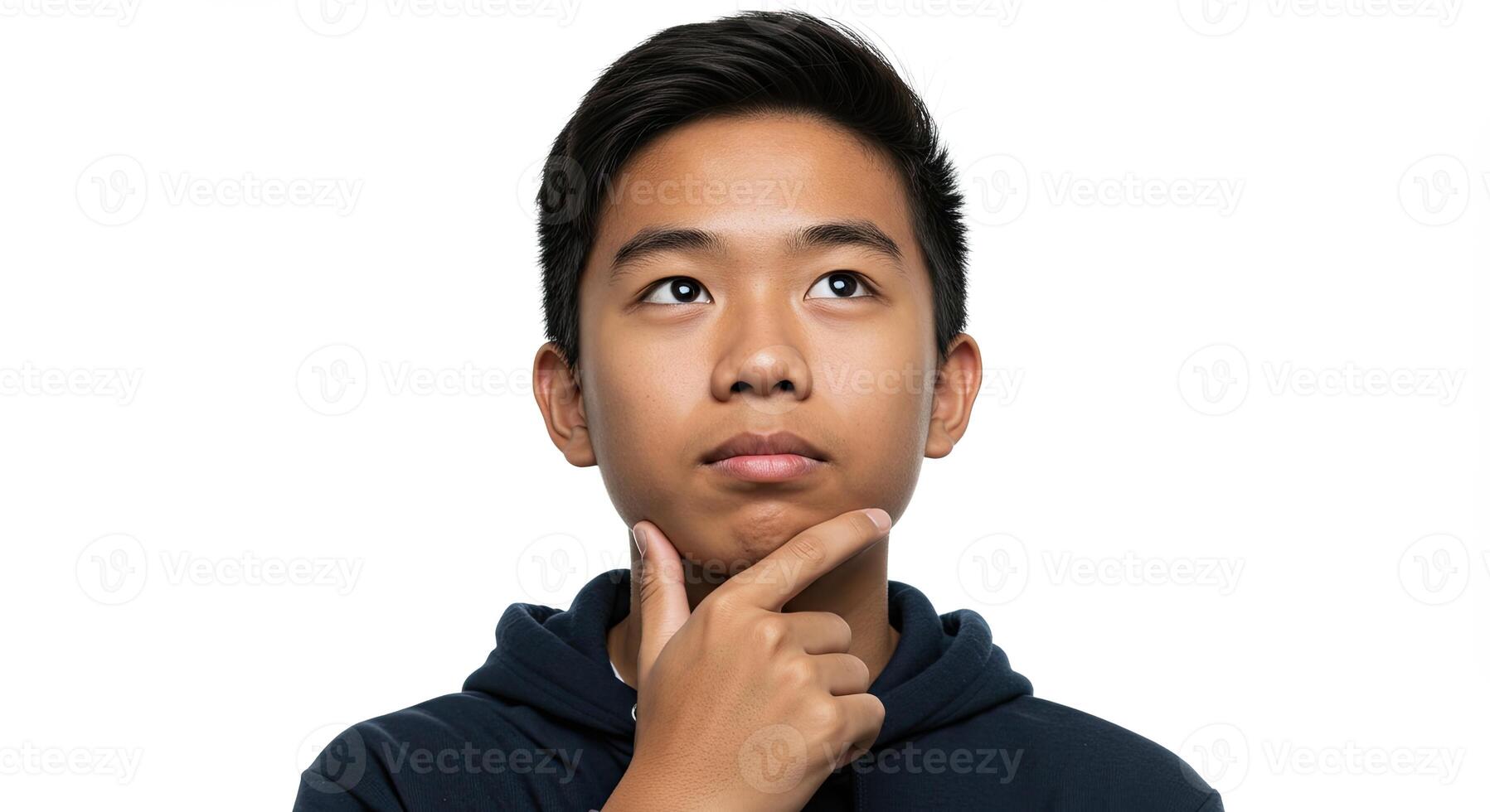 Thoughtful young Asian man contemplates with hand on chin looking up photo