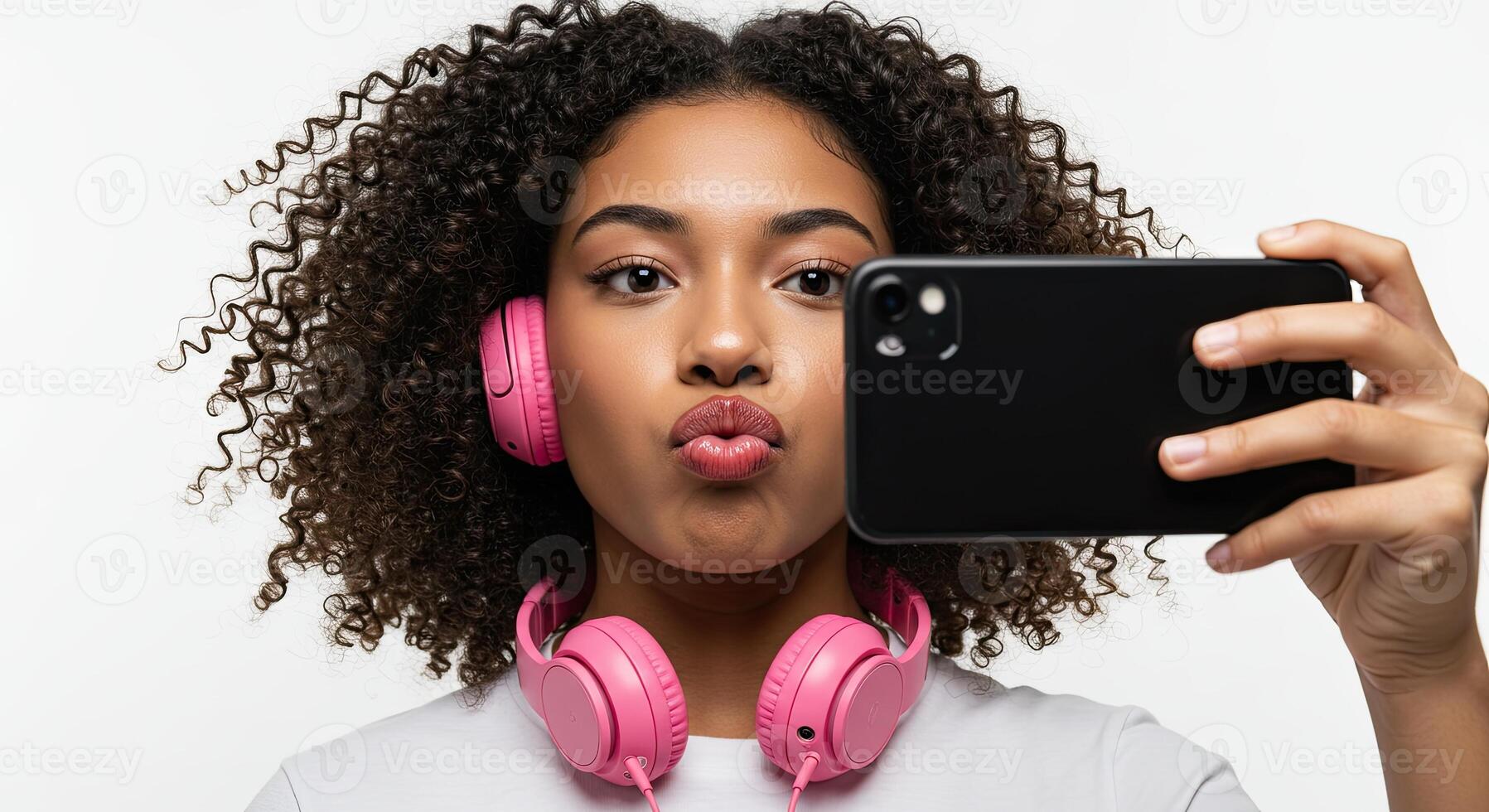 Young woman with curly hair takes a selfie with pink headphones photo