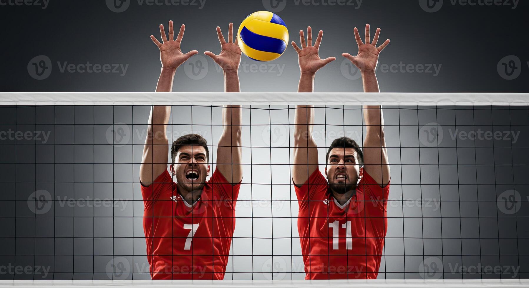 Two determined volleyball players blocking a spike over the net with focus photo