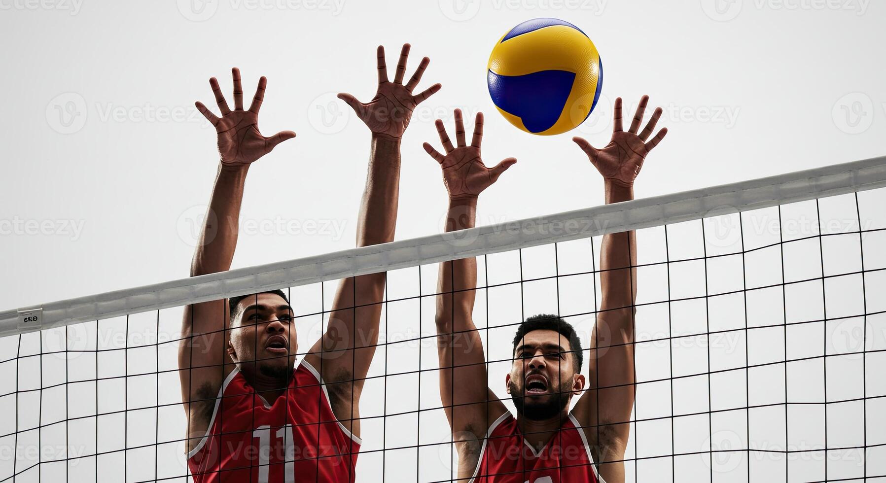 Two male volleyball players jumping to block a spike over the net in a match photo