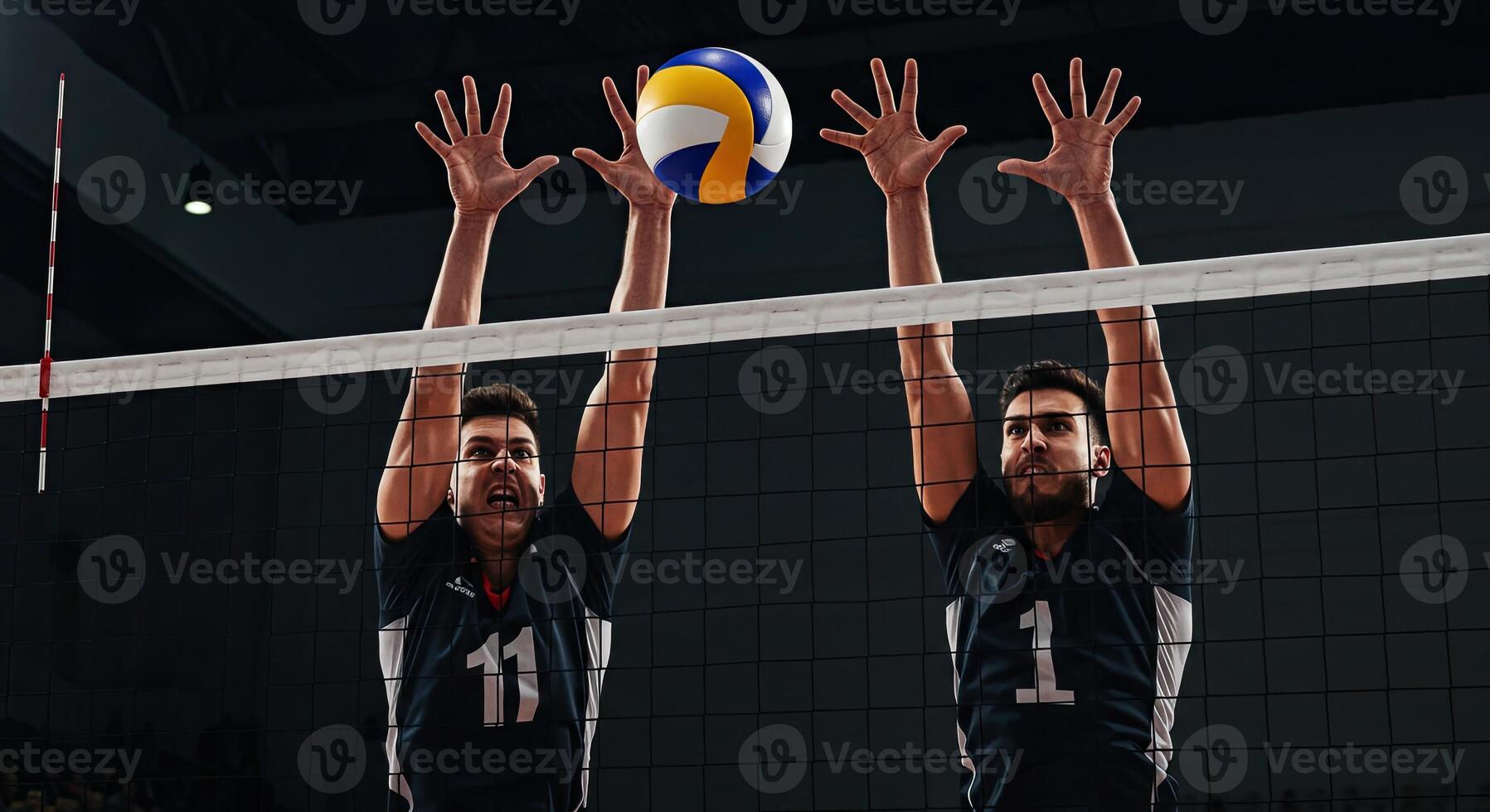 Two male volleyball players jumping to block a volleyball during a match game photo