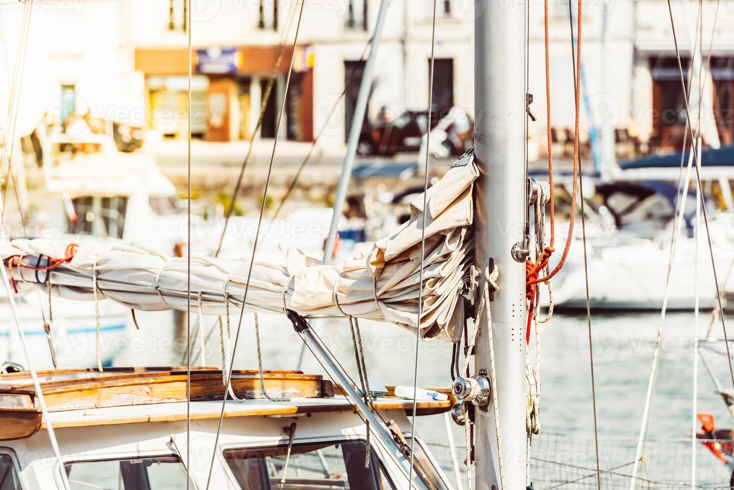 Sailboat mast with ropes in bustling marina on sunny day, background photo