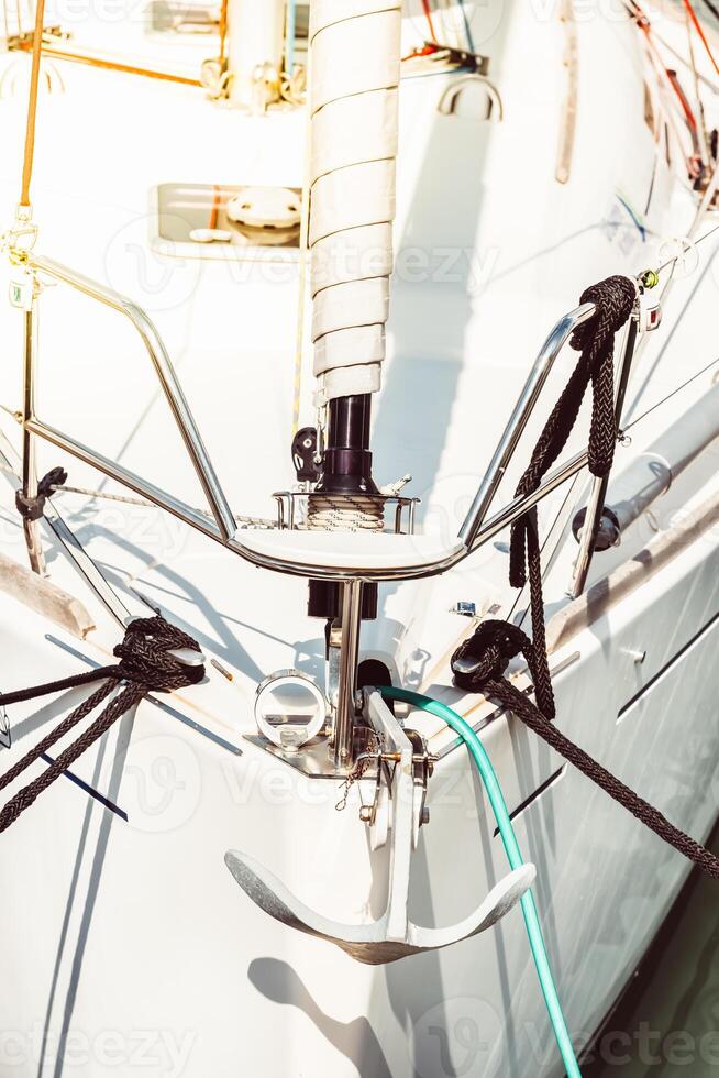 Sailboat anchor detail with ropes and white hull, suitable for background photo