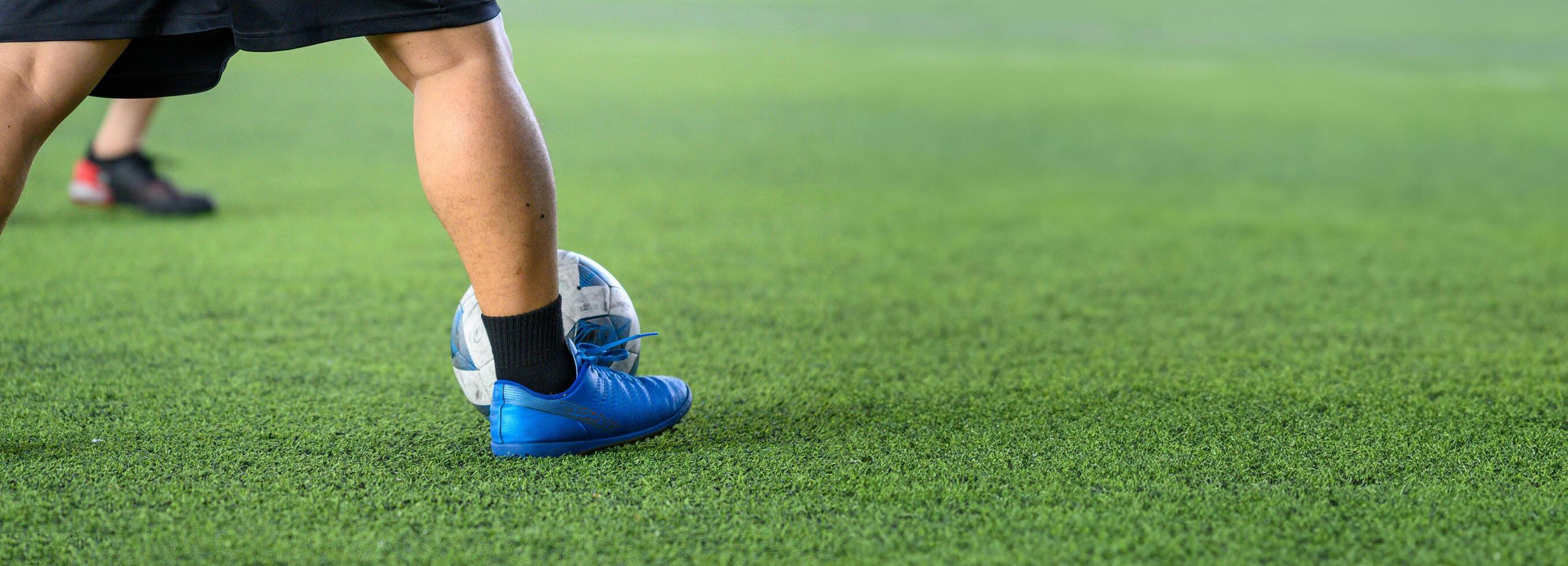 Soccer players in action on green grass field focusing on their legs and ball during game, showing movement and sports energy in close up view photo