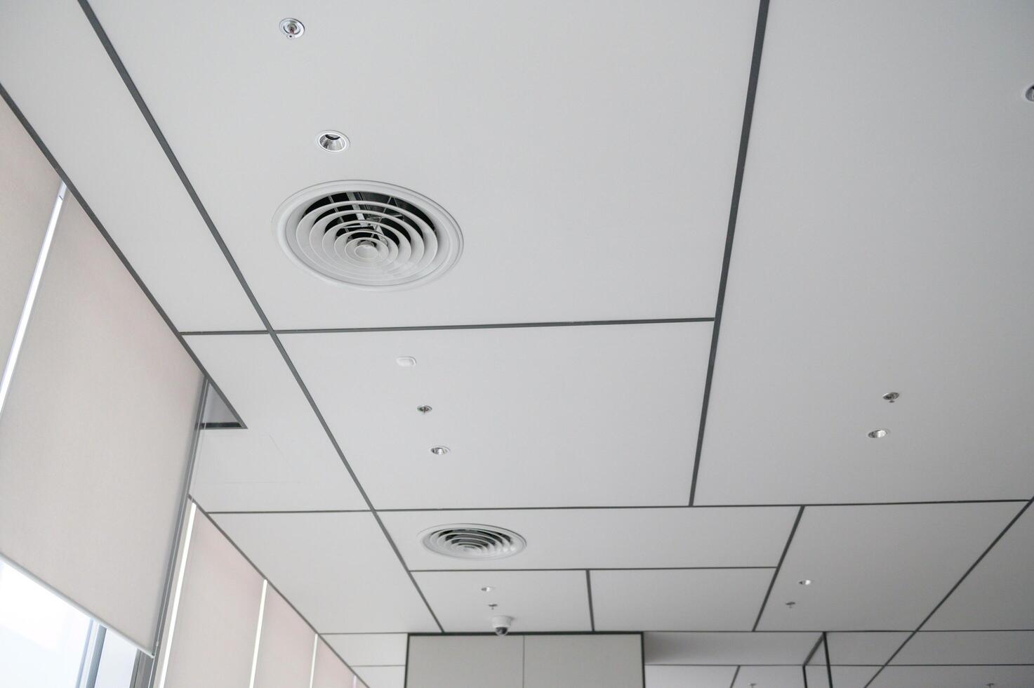 Clean modern office ceiling featuring air vents, recessed lighting, and grid pattern that creates bright and organized atmosphere. design is simple and functional photo