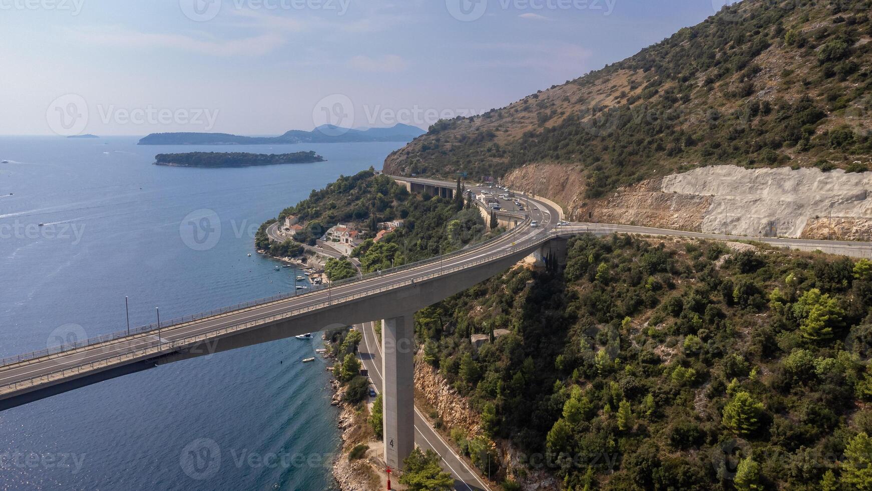 Aerial view of a suspension bridge over the Adriatic Sea near mountain. Travelling with car in summer in Croatia photo