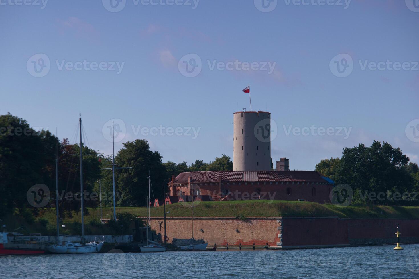 Historical fortress stands majestically by the waterfront with a flag waving in the breeze on a clear day photo