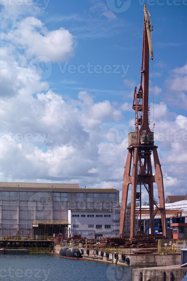 Historic crane by the harbor during a sunny day with scattered clouds in the background photo