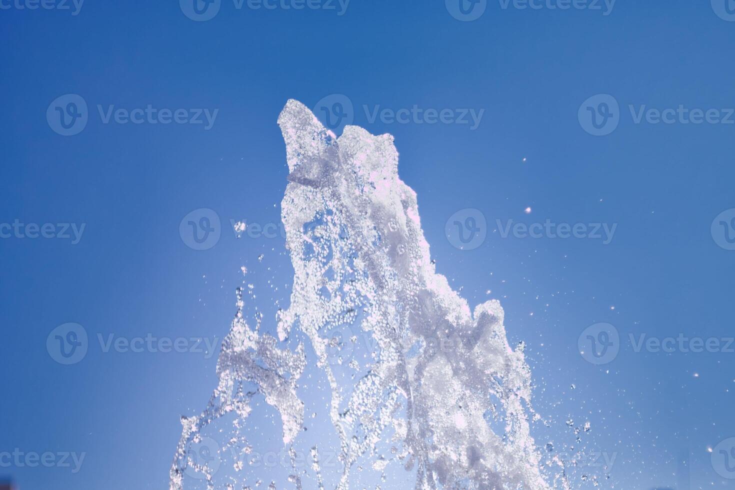 Water fountain spraying high into the clear blue sky during a sunny day in a public park photo