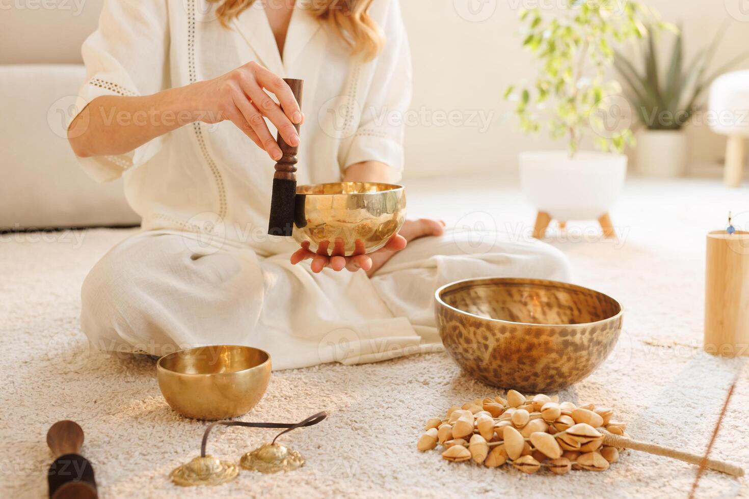 Hands using Tibetan singing bowl for meditation and sound therapy on cozy indoor carpet. photo