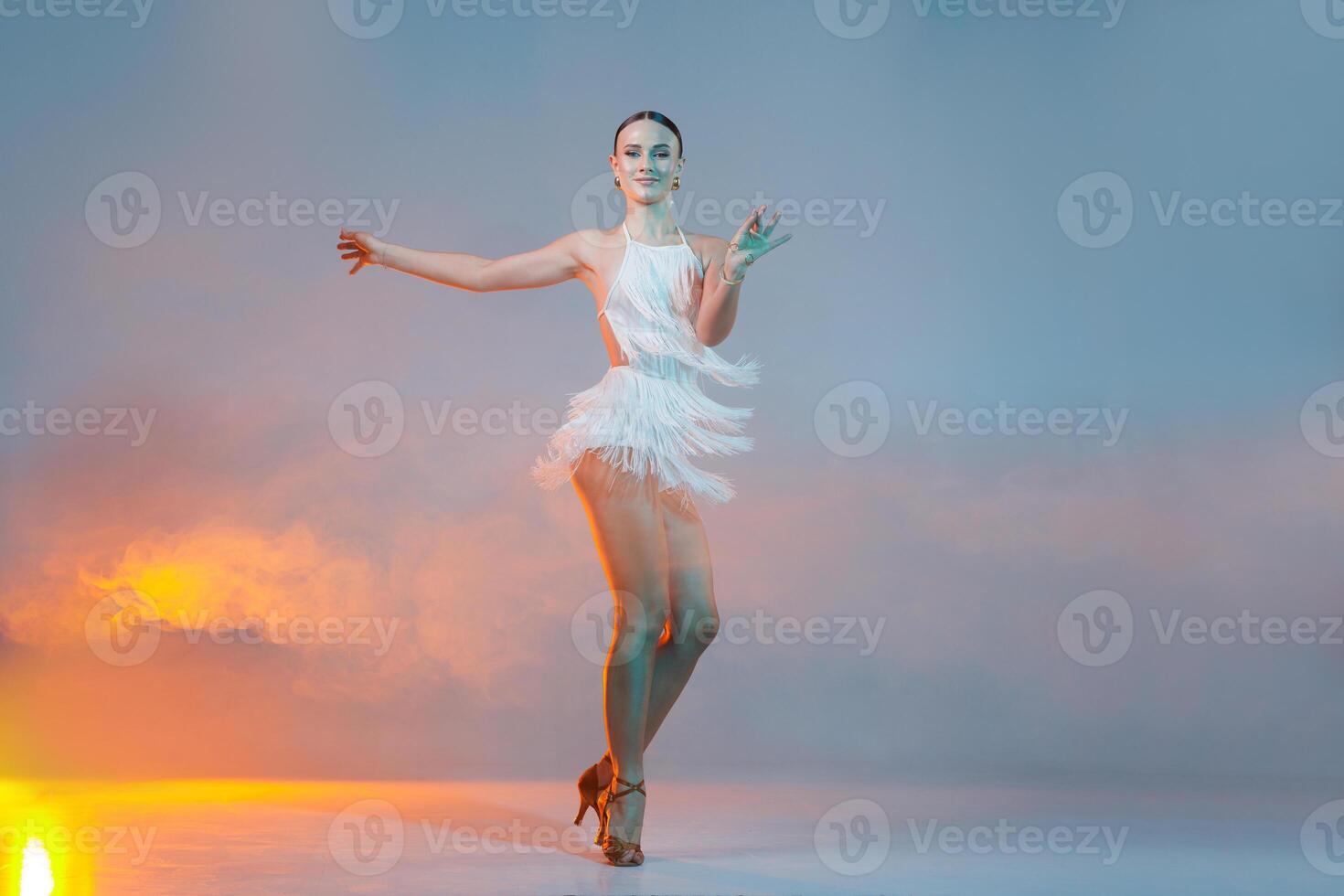 Female Latin dancer in motion with fringe dress and stage lights, striking a graceful pose. photo