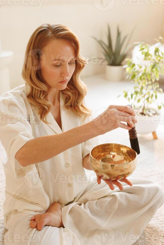 Focused woman using singing bowl for sound healing and mindfulness in peaceful environment. photo
