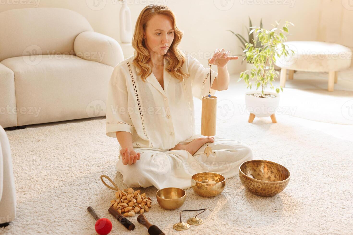 Serene woman using bamboo chime during sound therapy and meditation in cozy minimalist space. photo