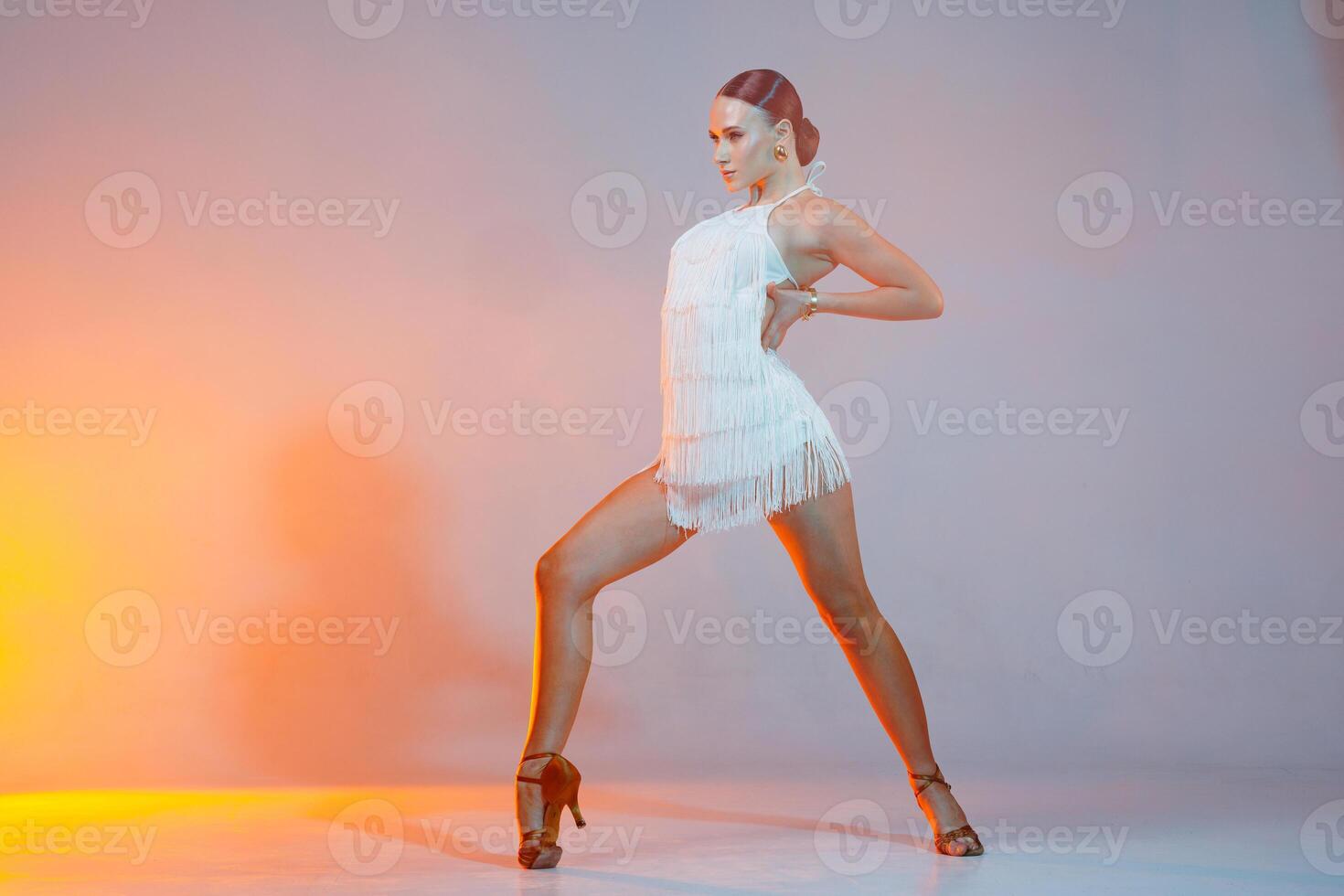 Latin dancer in dramatic lighting posing with strength and grace in a stylish fringe costume. photo