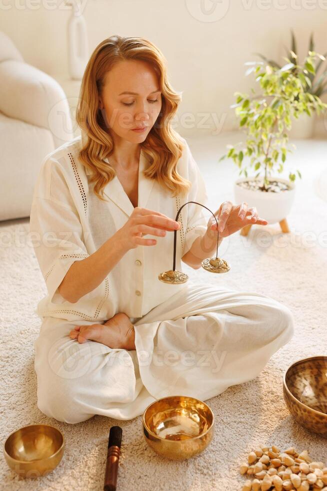 Woman using Tibetan cymbals in meditation, focused on balance, energy, and inner peace. photo