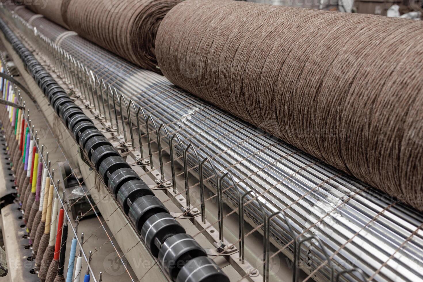 Brown yarn on textile machine in factory, with colorful thread guides and rollers in production. photo