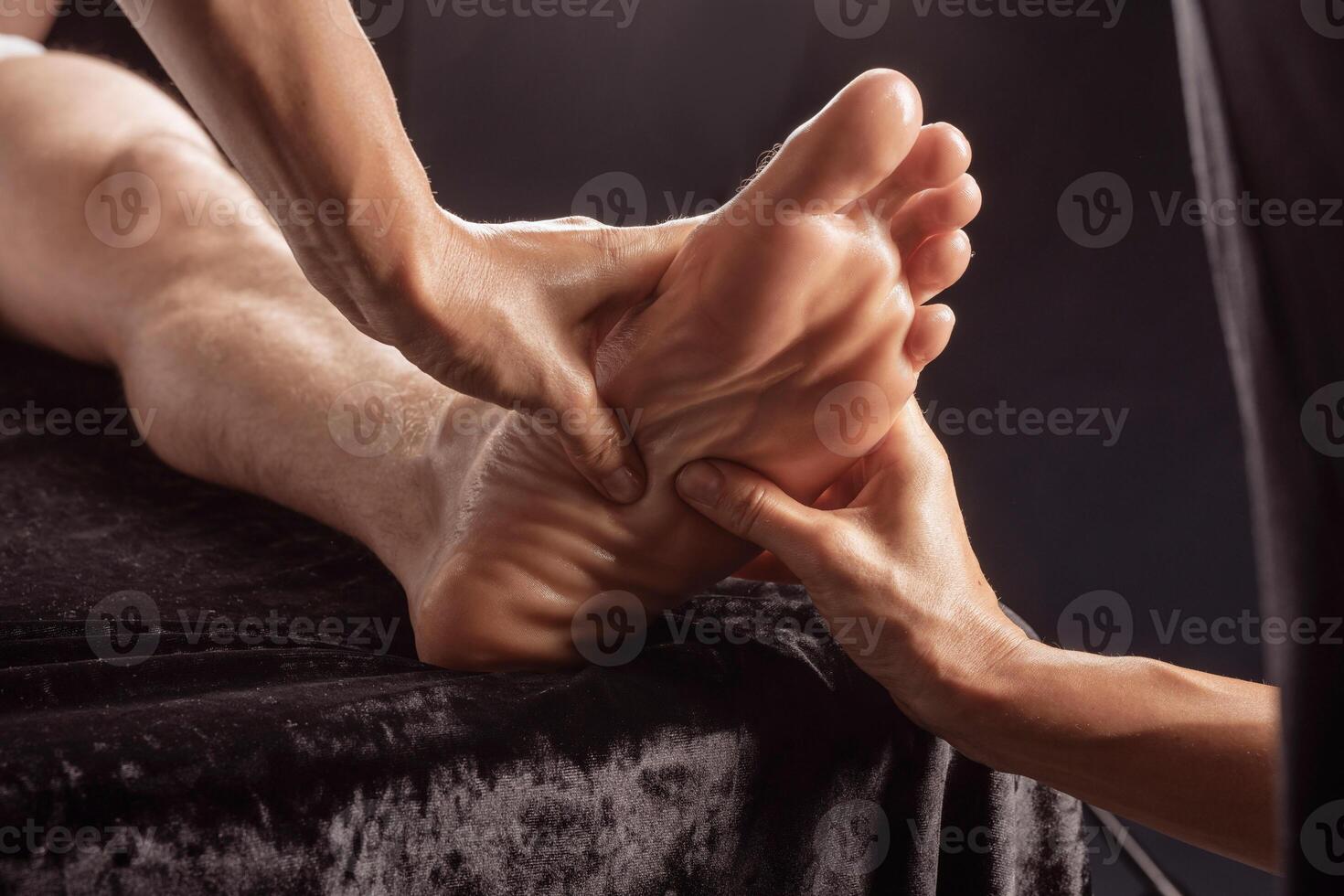 Therapist gives foot massage using pressure techniques for relaxation and muscle relief. photo