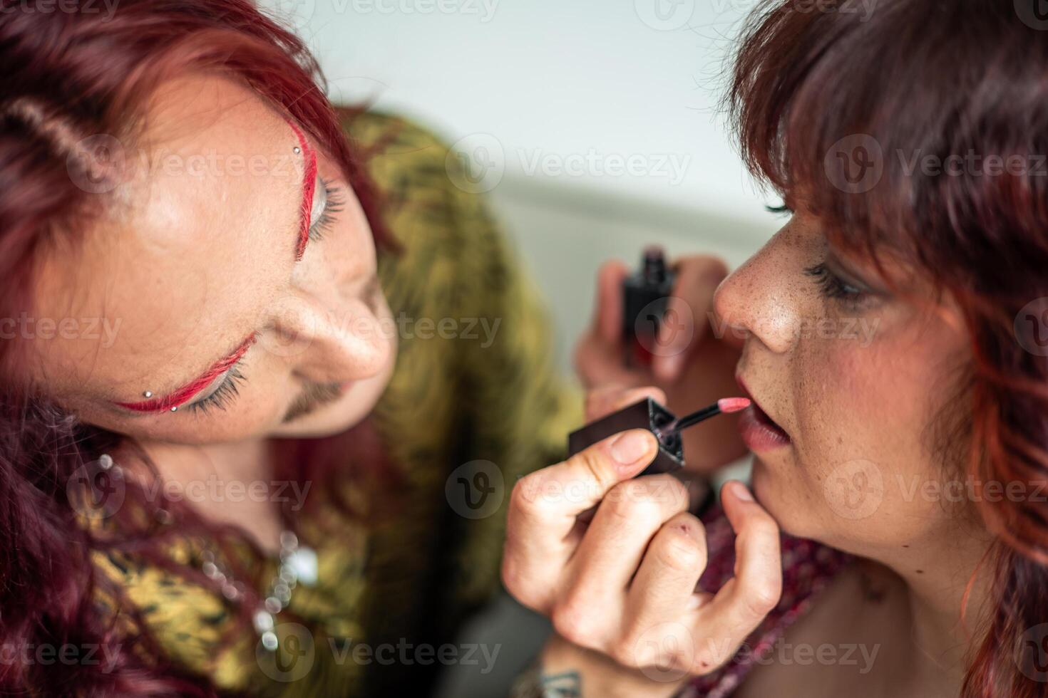 Non-binary person applying lipstick on friend celebrating body positivity photo
