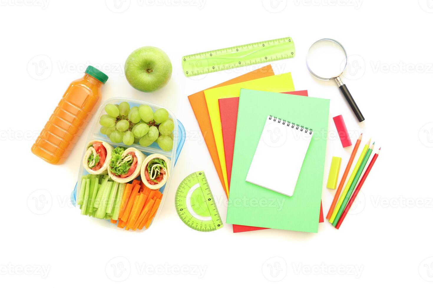 Brightly colored stationery and fresh snacks laid out on white surface, showcasing preparation for study session or project work. Healthy options include fruits and vegetables. photo