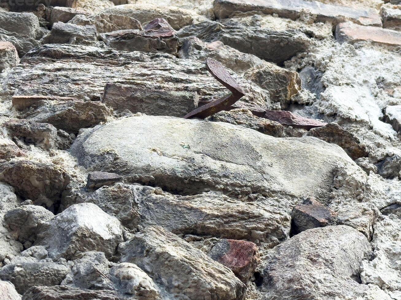 Ancient stone wall with metal hooks in weathered condition photo