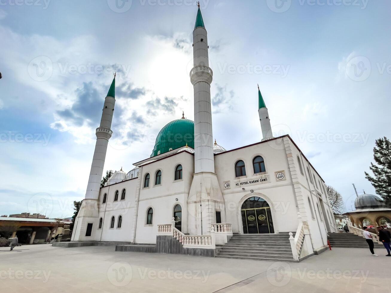 Elegant Islamic Mosque Exterior with Minarets and Green Dome under a Blue Sky photo