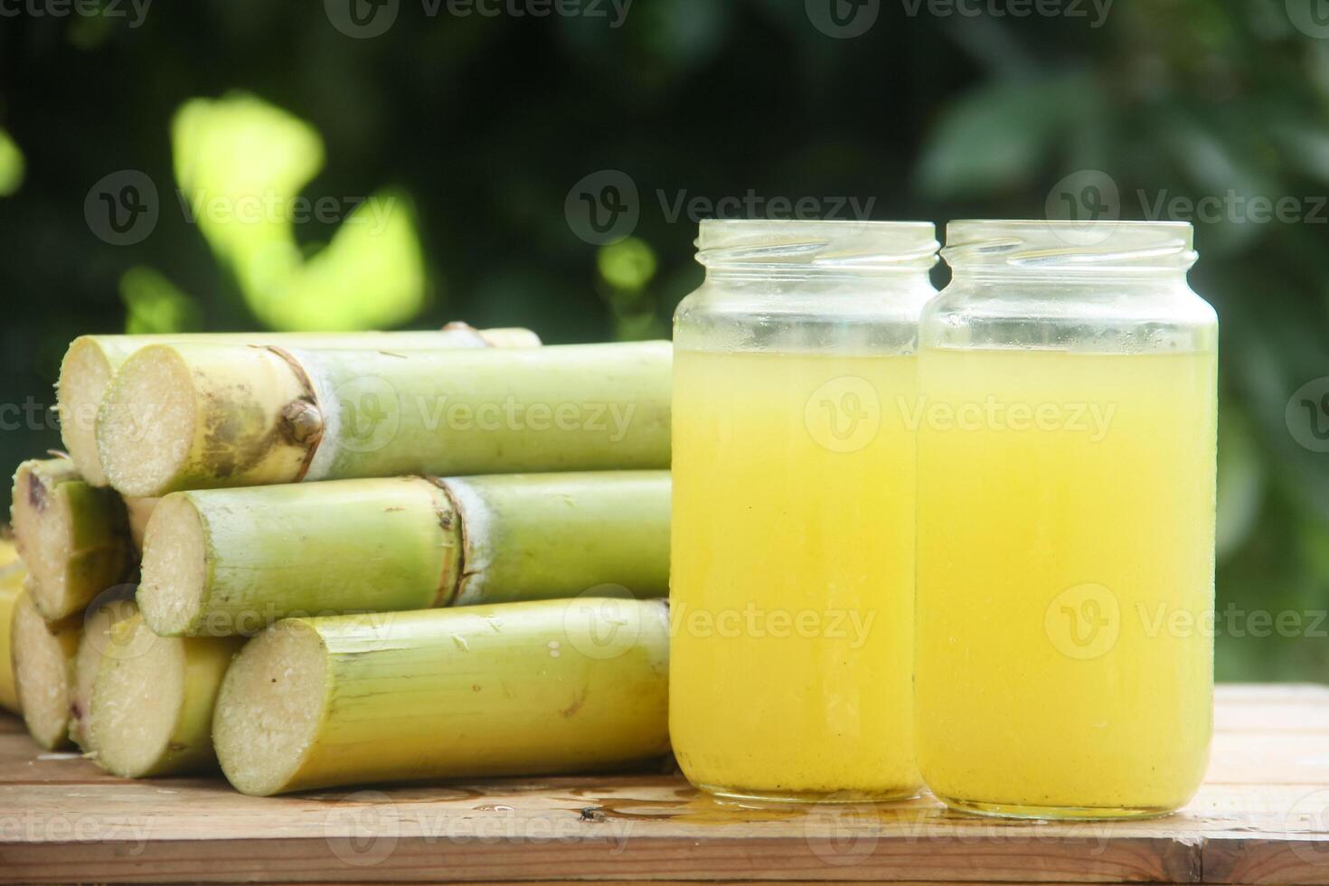 Two jars of sugarcane juice next to a pile of sticks photo